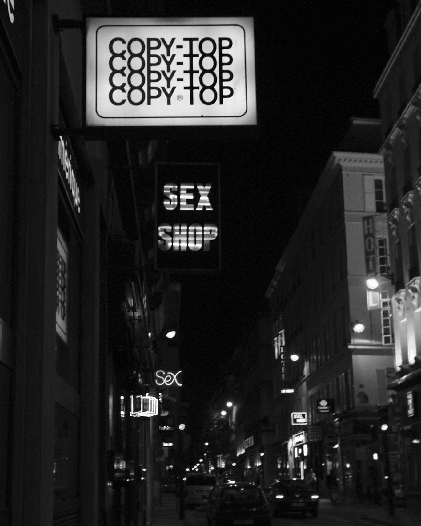 Night street with lit signs: Copy-Top repeated four times, Sex Shop, hotels