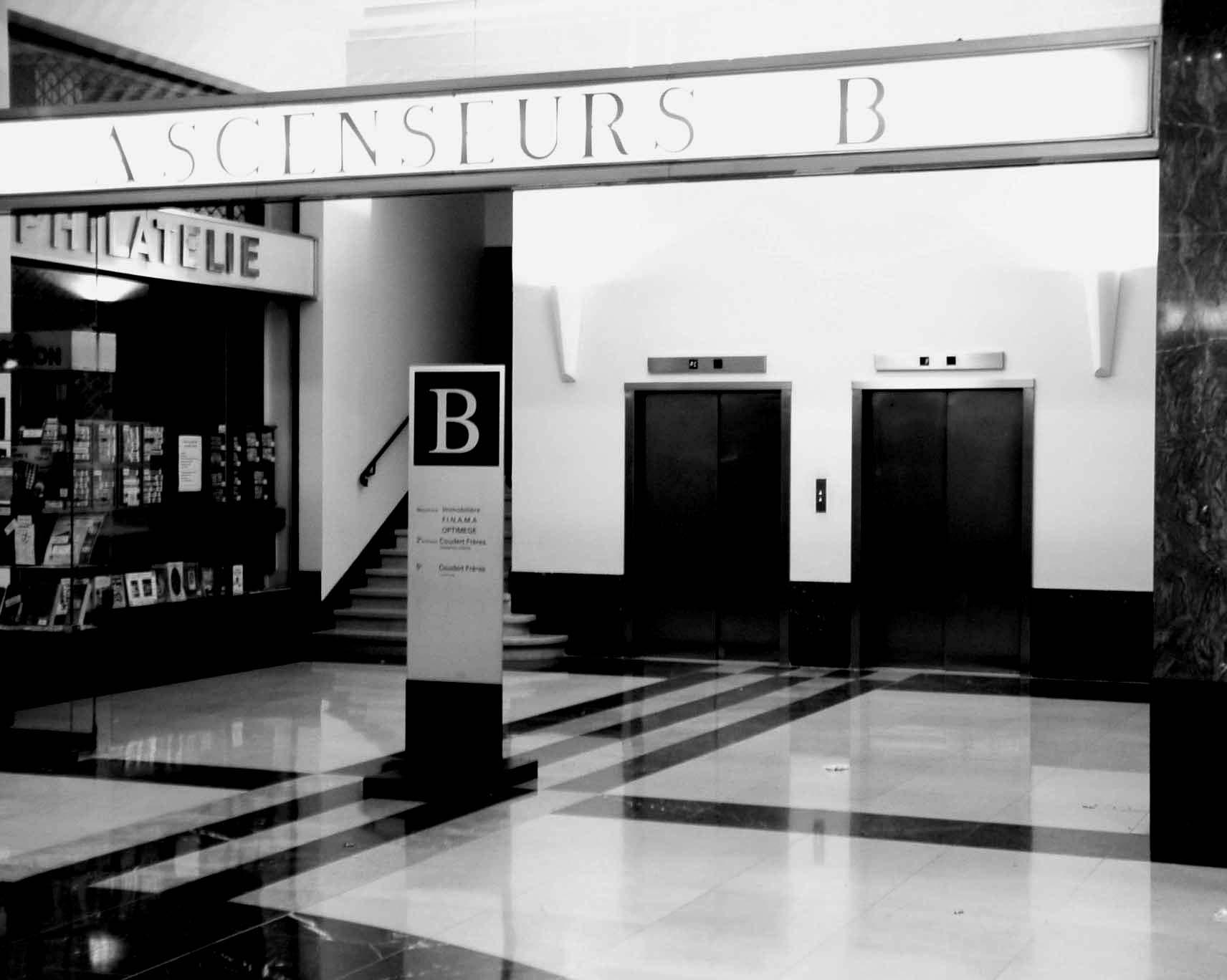 Lobby with the sign Ascenseurs B, lift doors and a philately shop