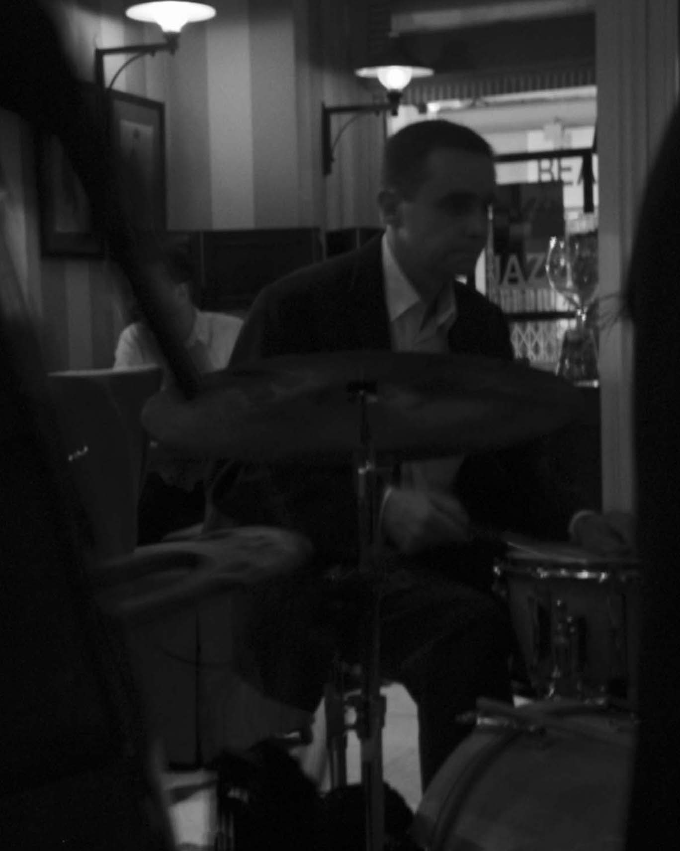Jazz drummer behind his cymbal in a dim bar