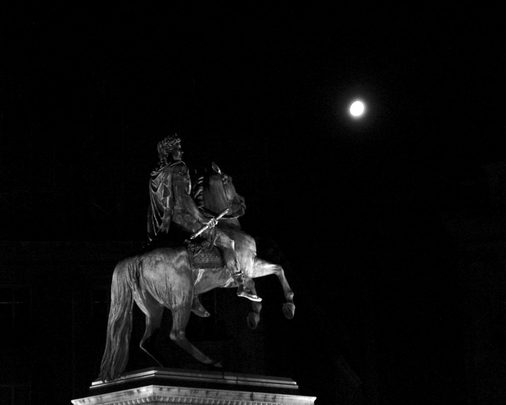 Equestrian statue against a black sky with the moon