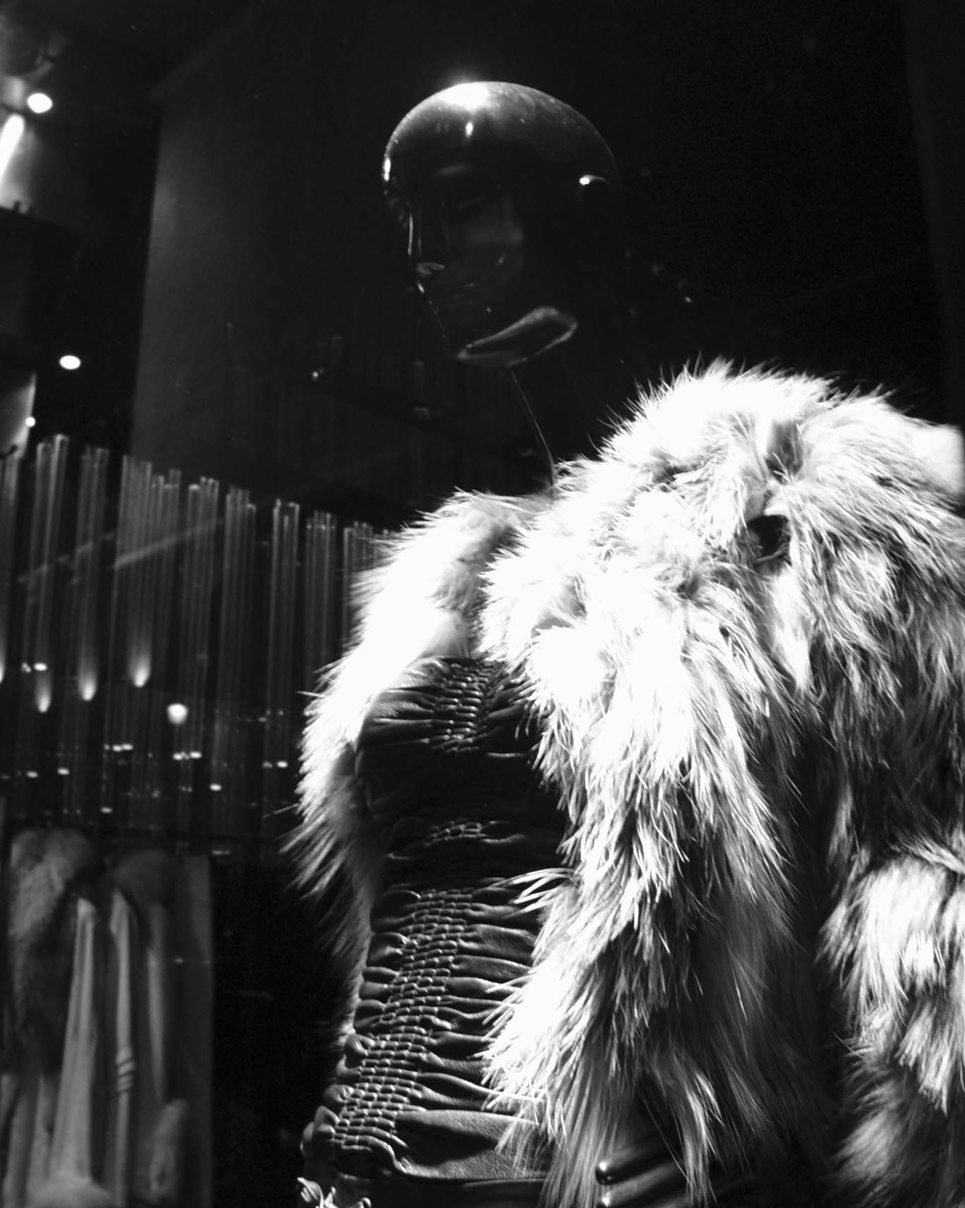 Mannequin in a fur jacket in a shop window at night