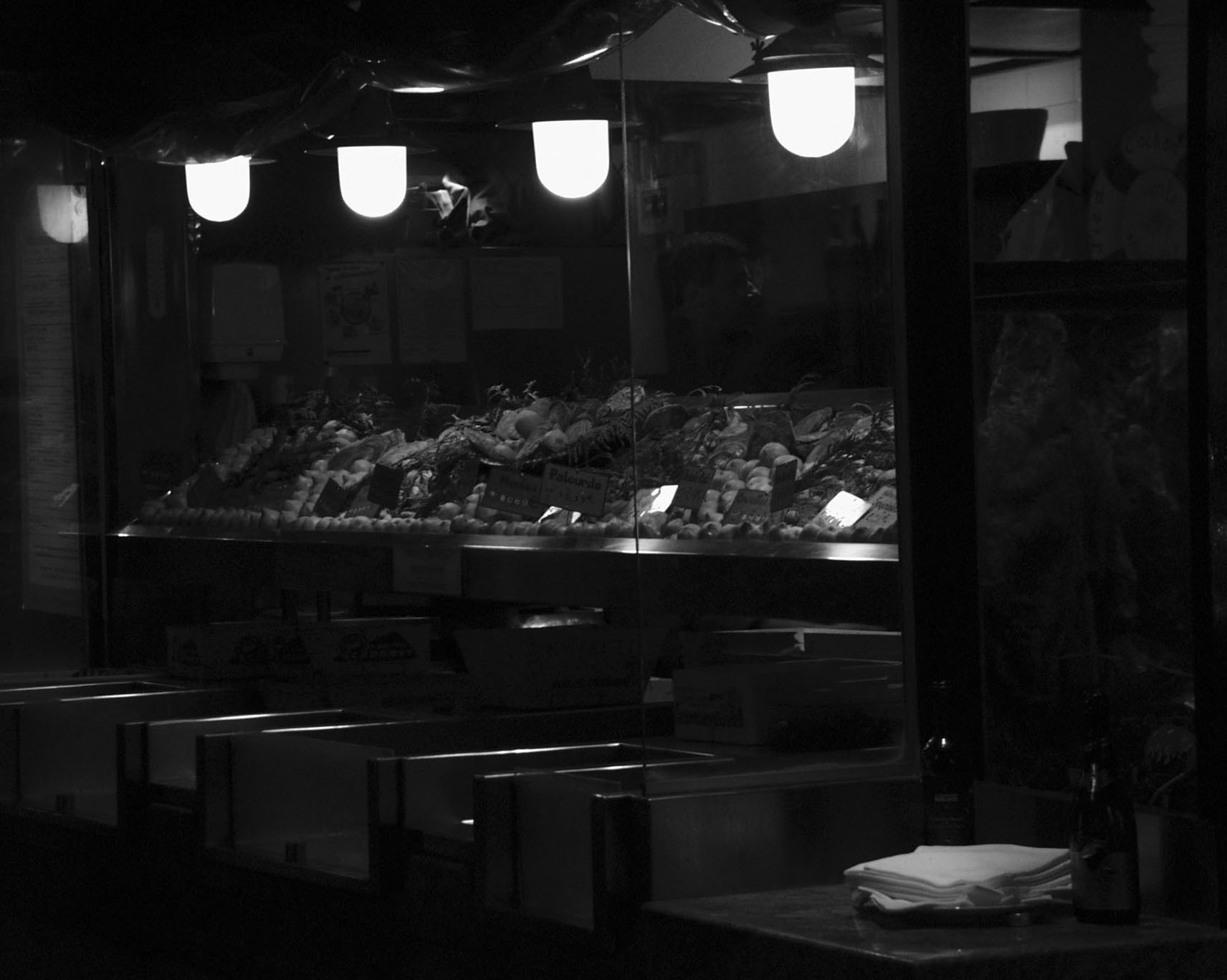 Seafood display under four hanging lamps in a dark brasserie