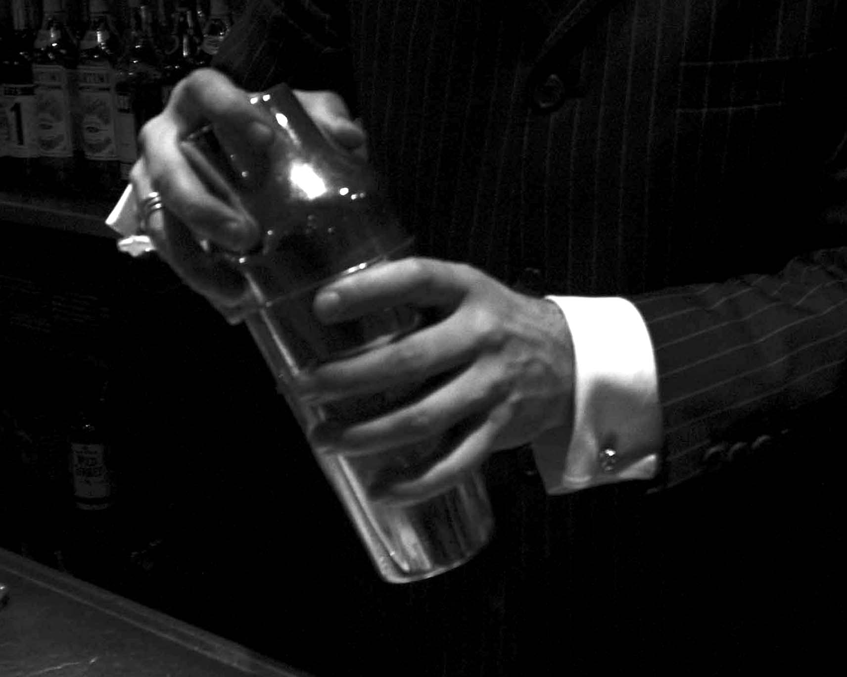 Bartender’s hands in a pinstripe suit shaking a cocktail