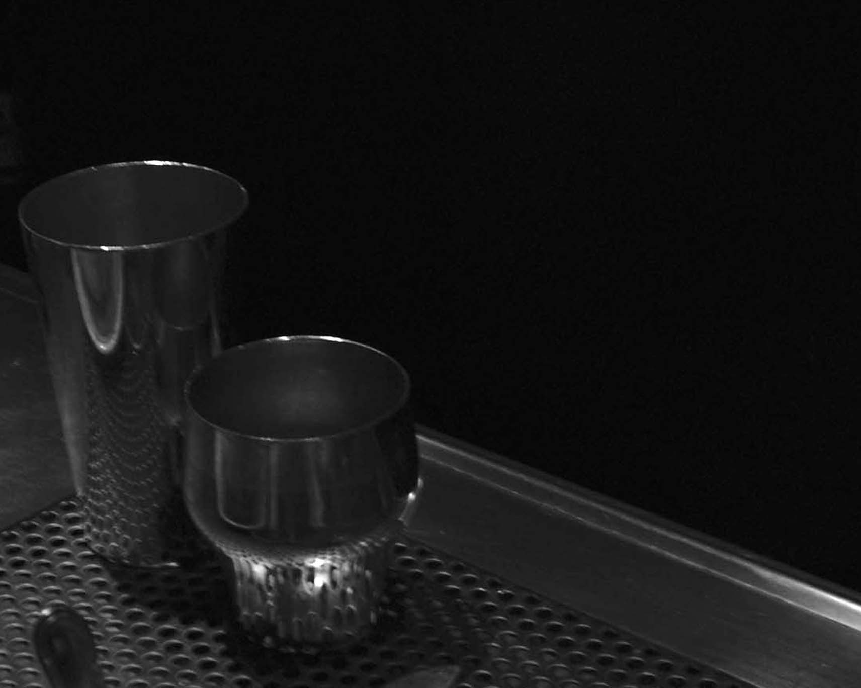 Two metal cocktail shakers on a bar drain tray