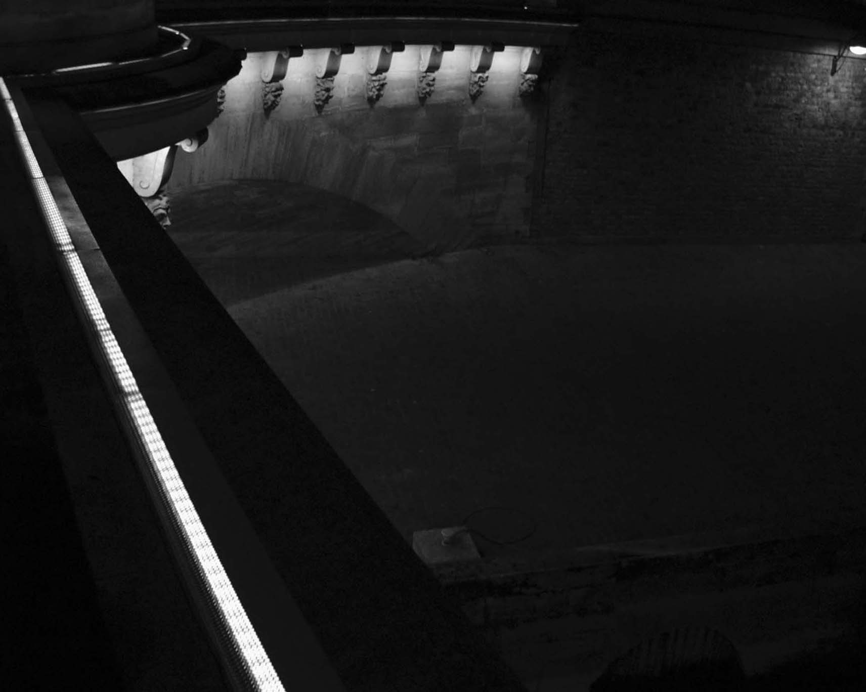 Underside of the Pont Neuf with its carved masks lit above dark water