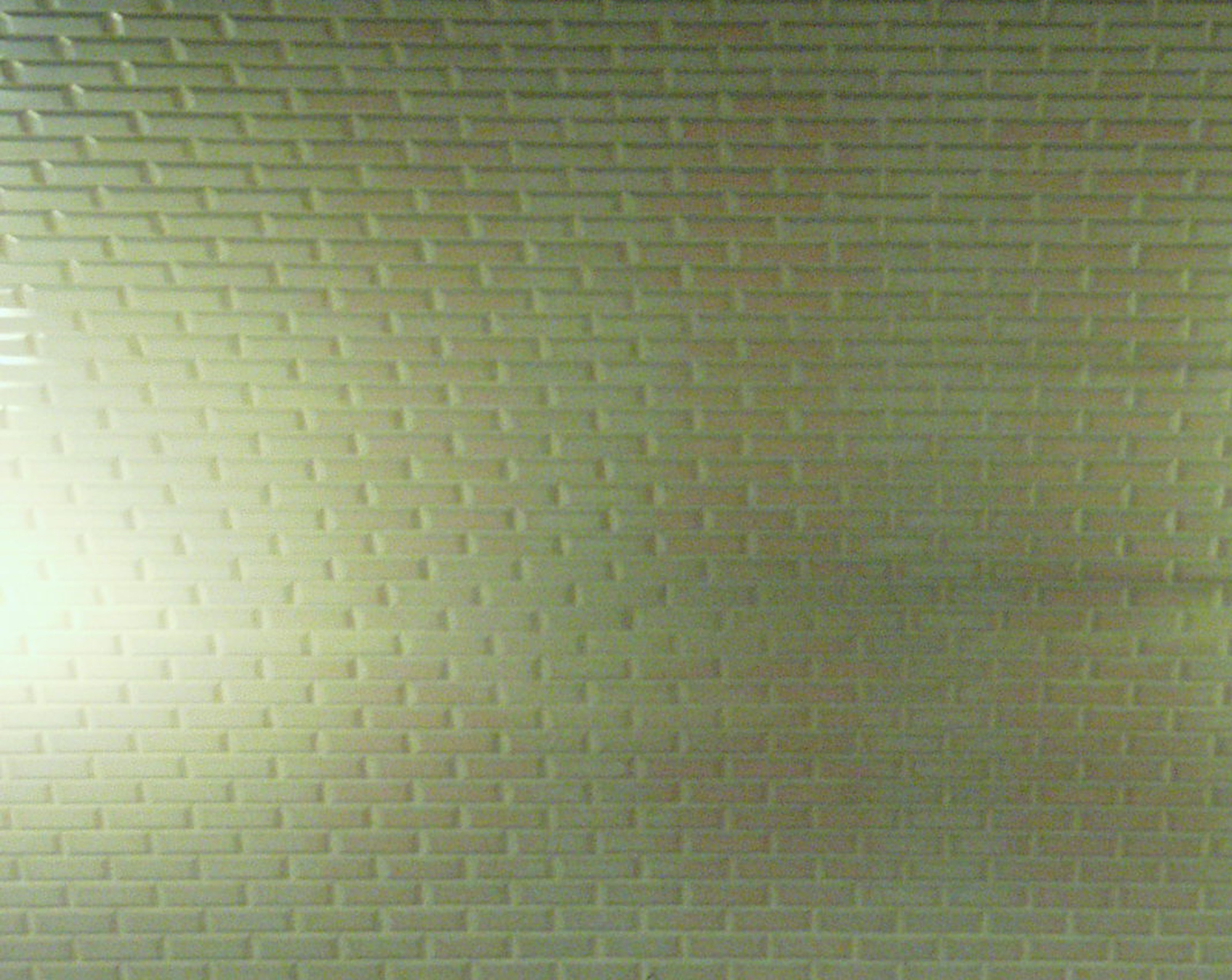 A tiled wall in green light, bright on the left