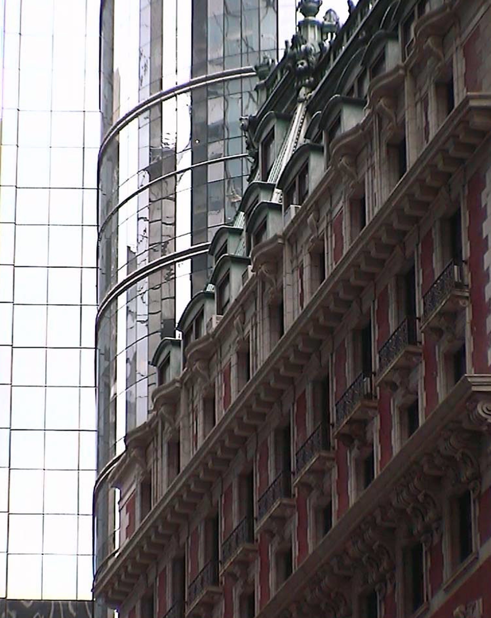 A glass tower beside an ornate red stone façade