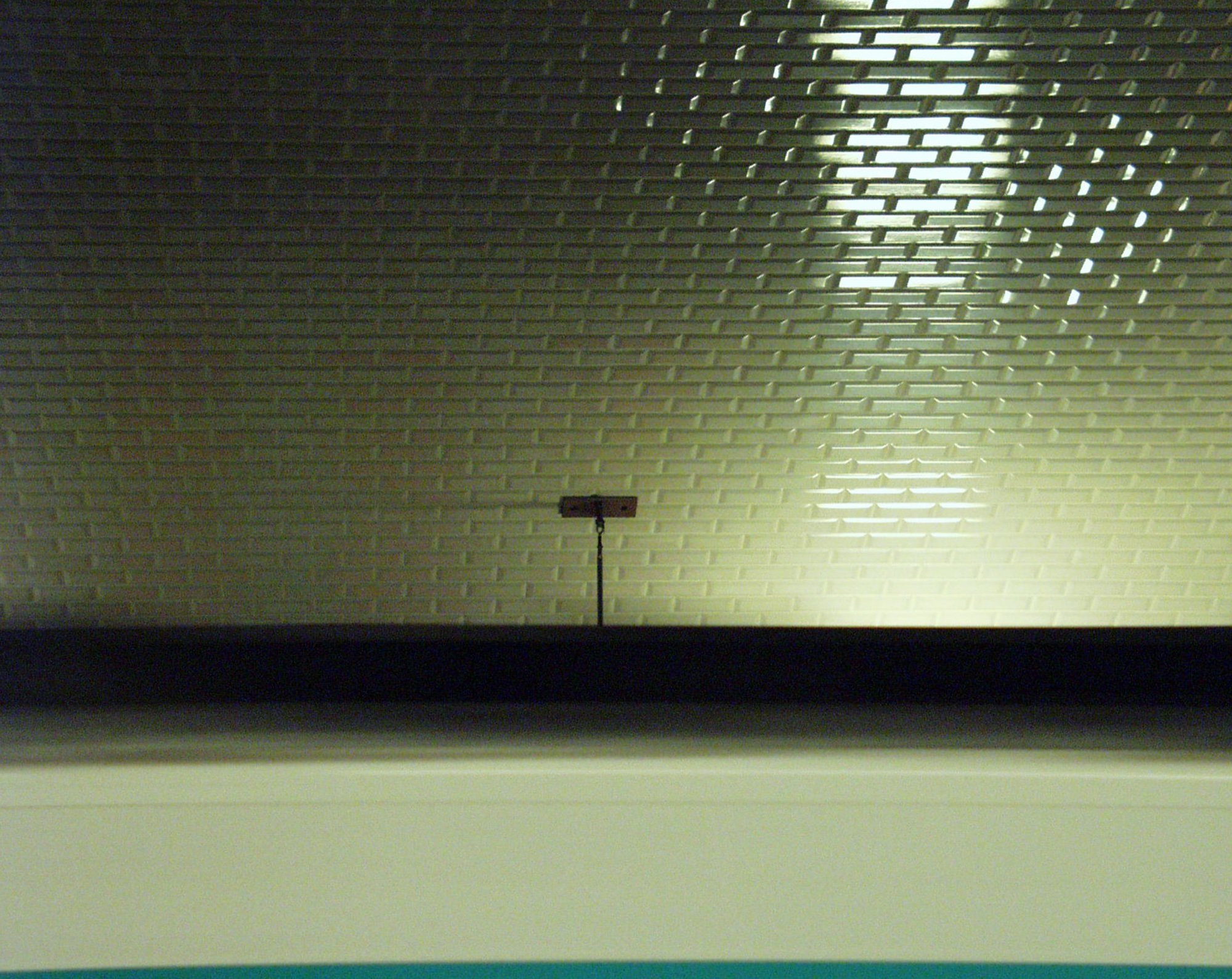 Tiled métro wall in green light over the edge of a platform