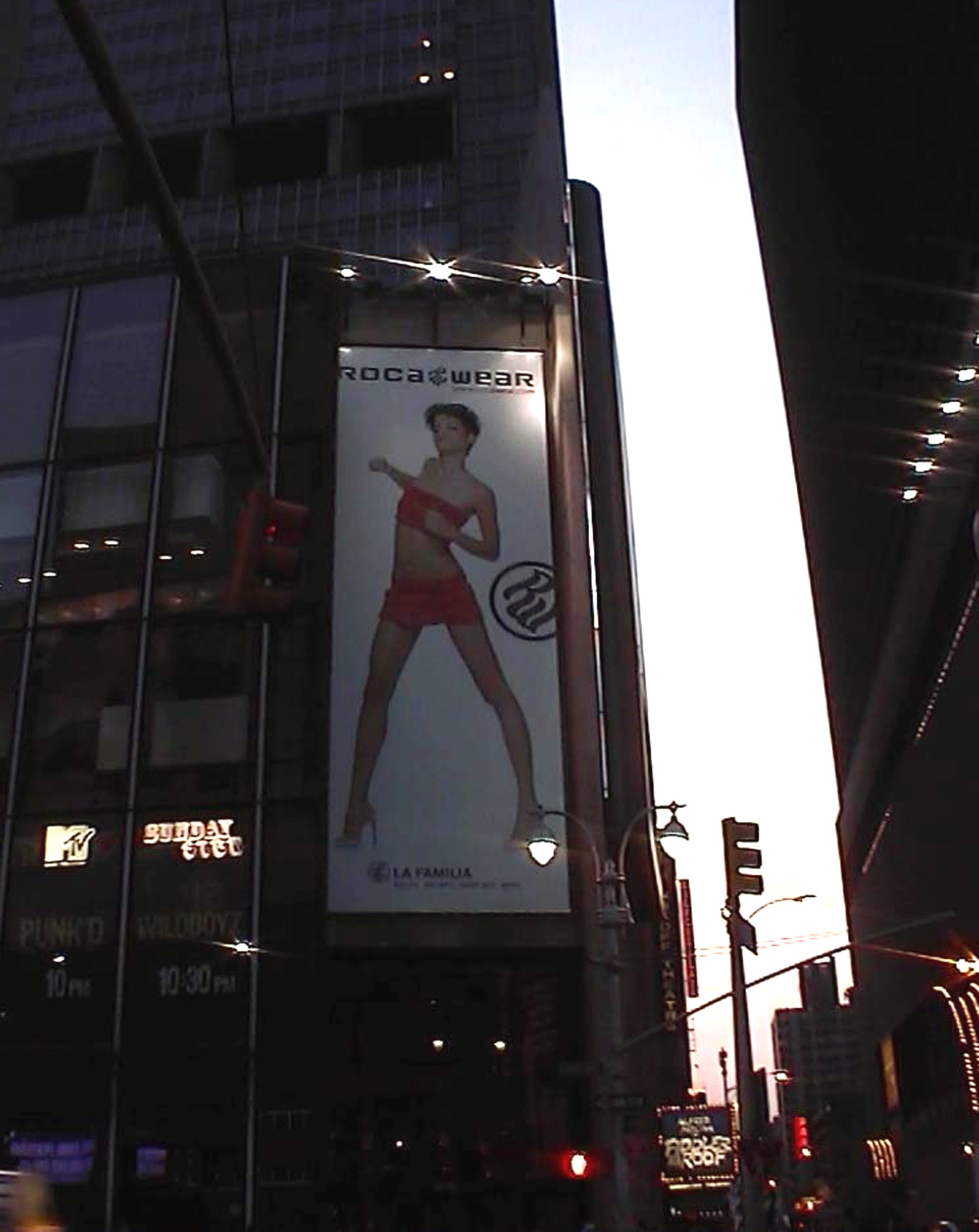 Billboard of a woman in red between dark towers at dusk