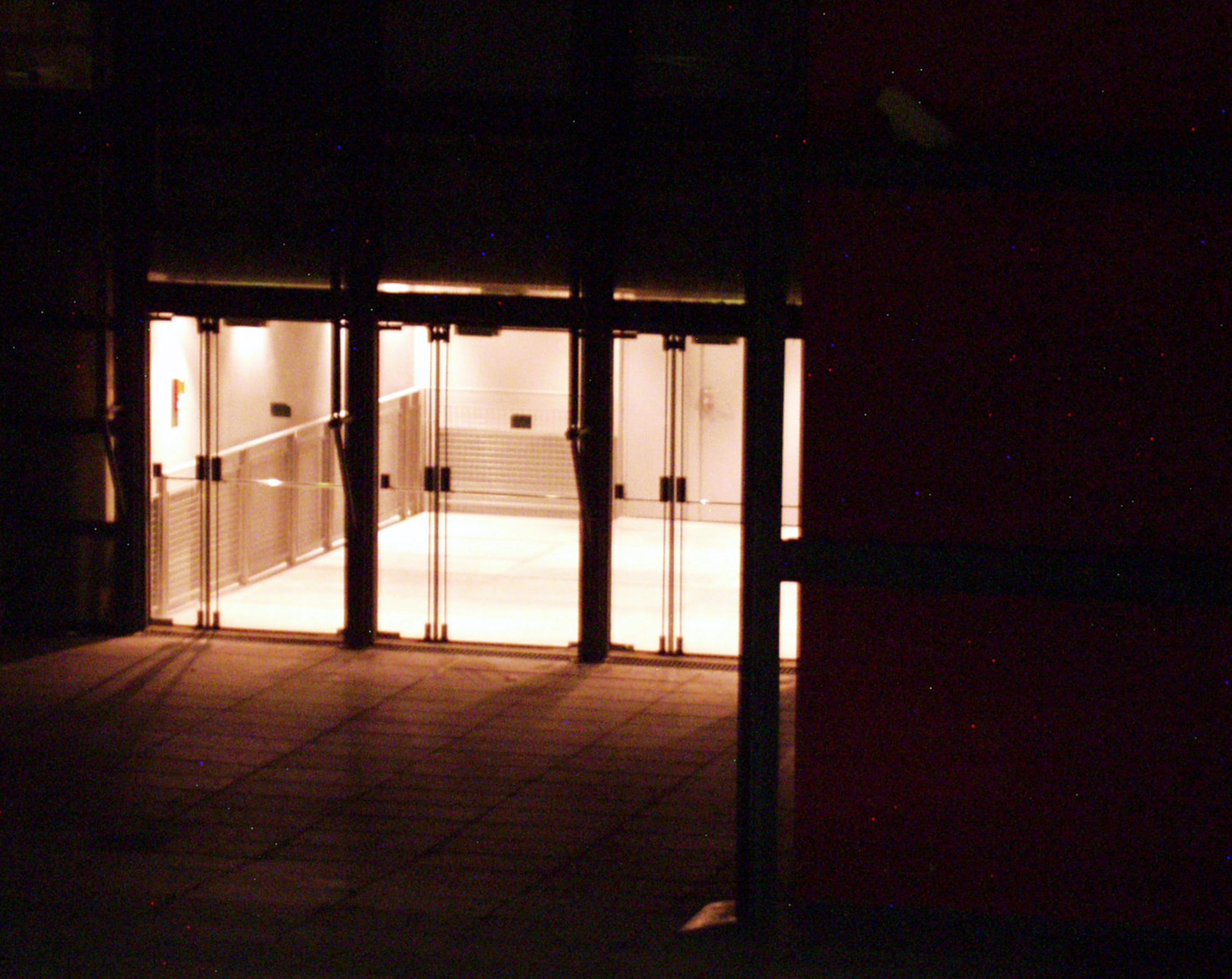 Lit glass doors at the end of a dark entrance