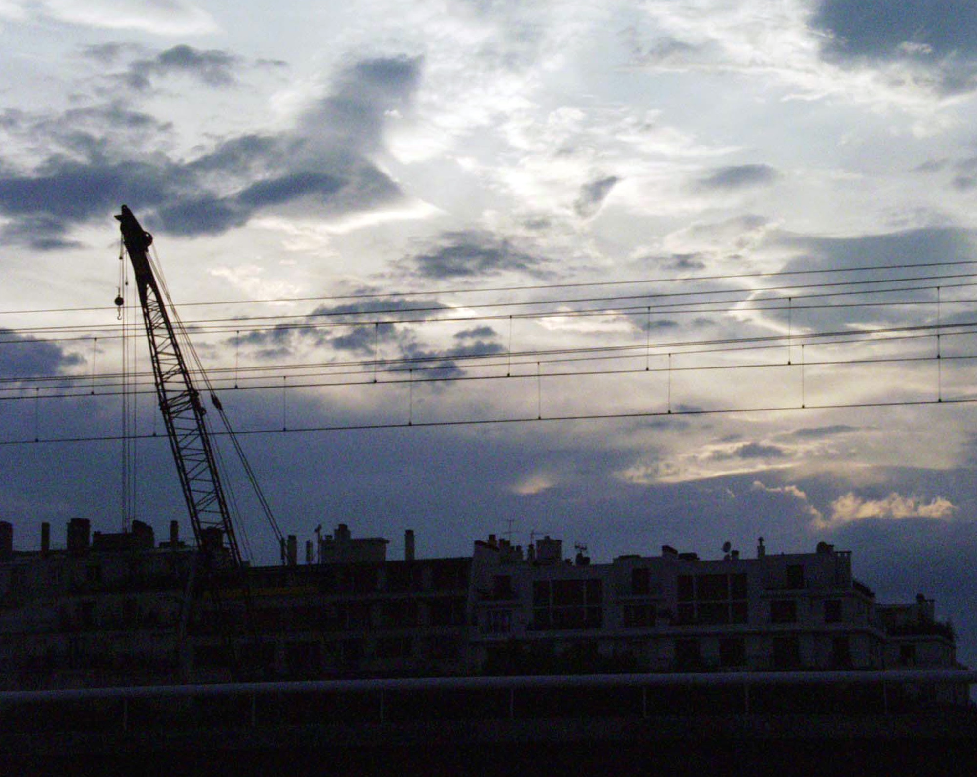 Silhouette of a crane and rooftops against an evening sky