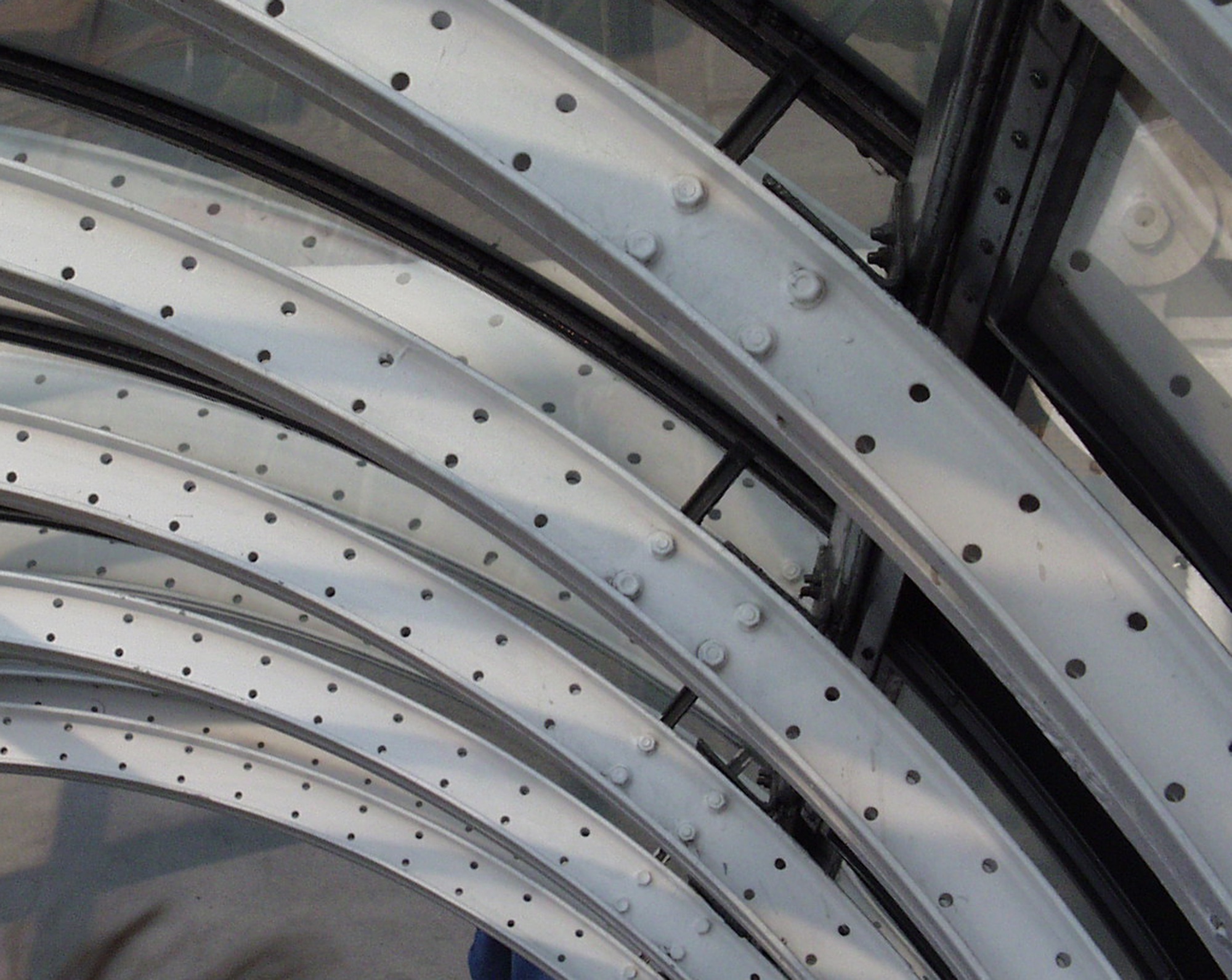 Curved white steel ribs studded with rivets