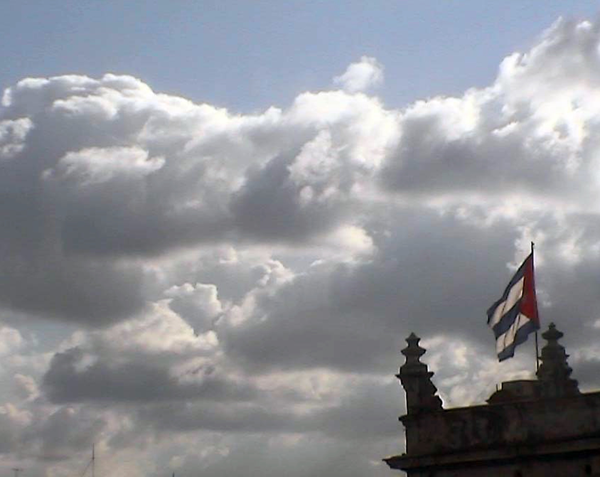 Clouds over Havana, a Cuban flag on top of a building