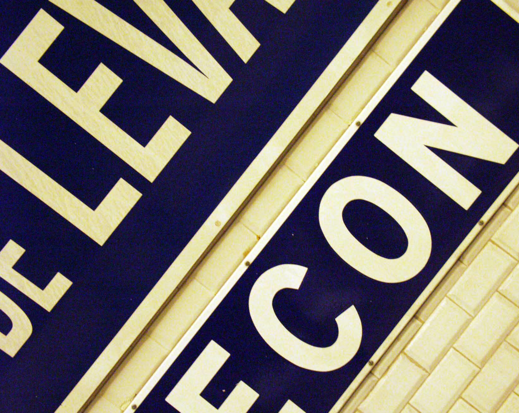 Métro station sign seen at an angle, the letters CON in white on blue