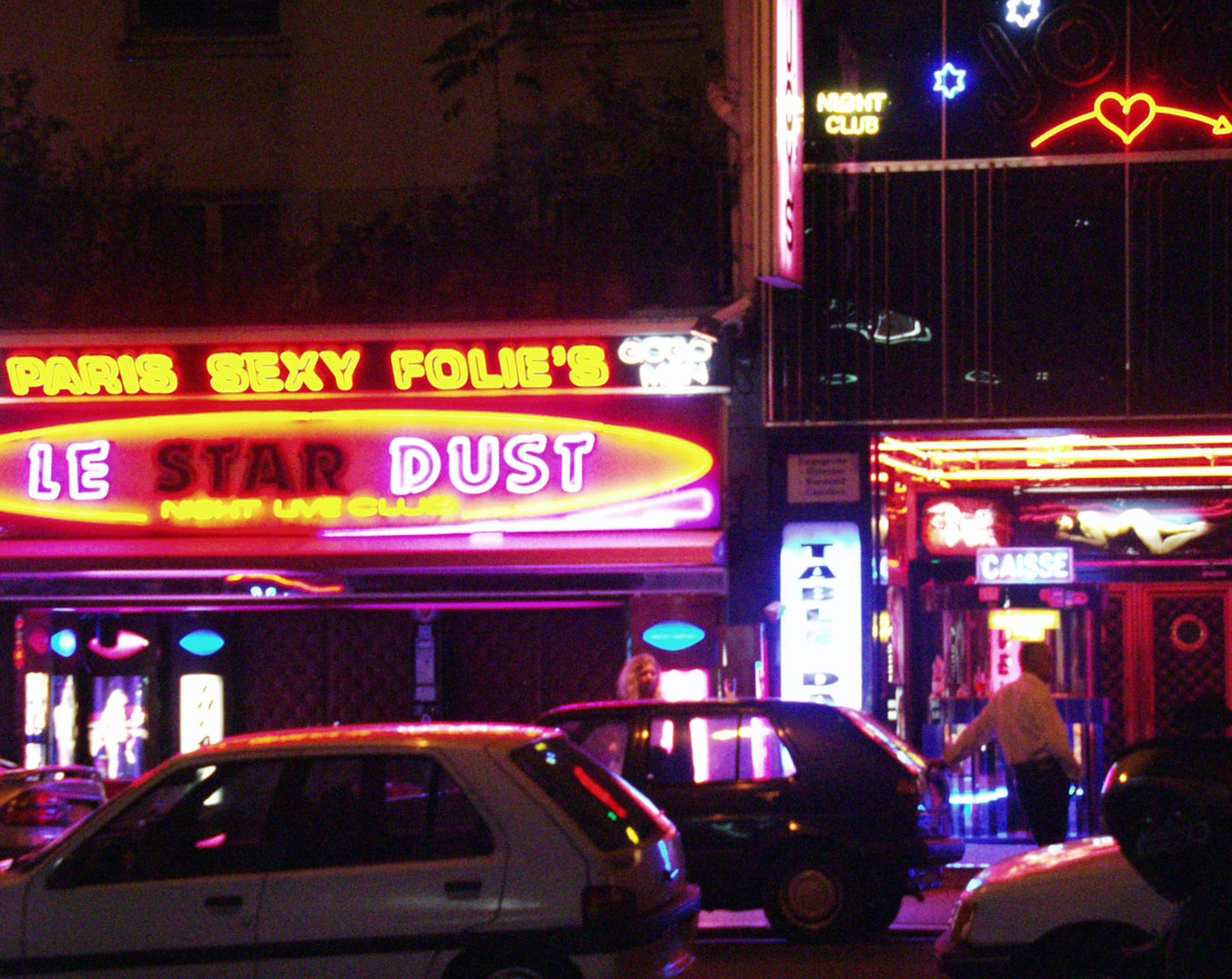 Paris Sexy Folie's and Le Star Dust neon above a street of parked cars