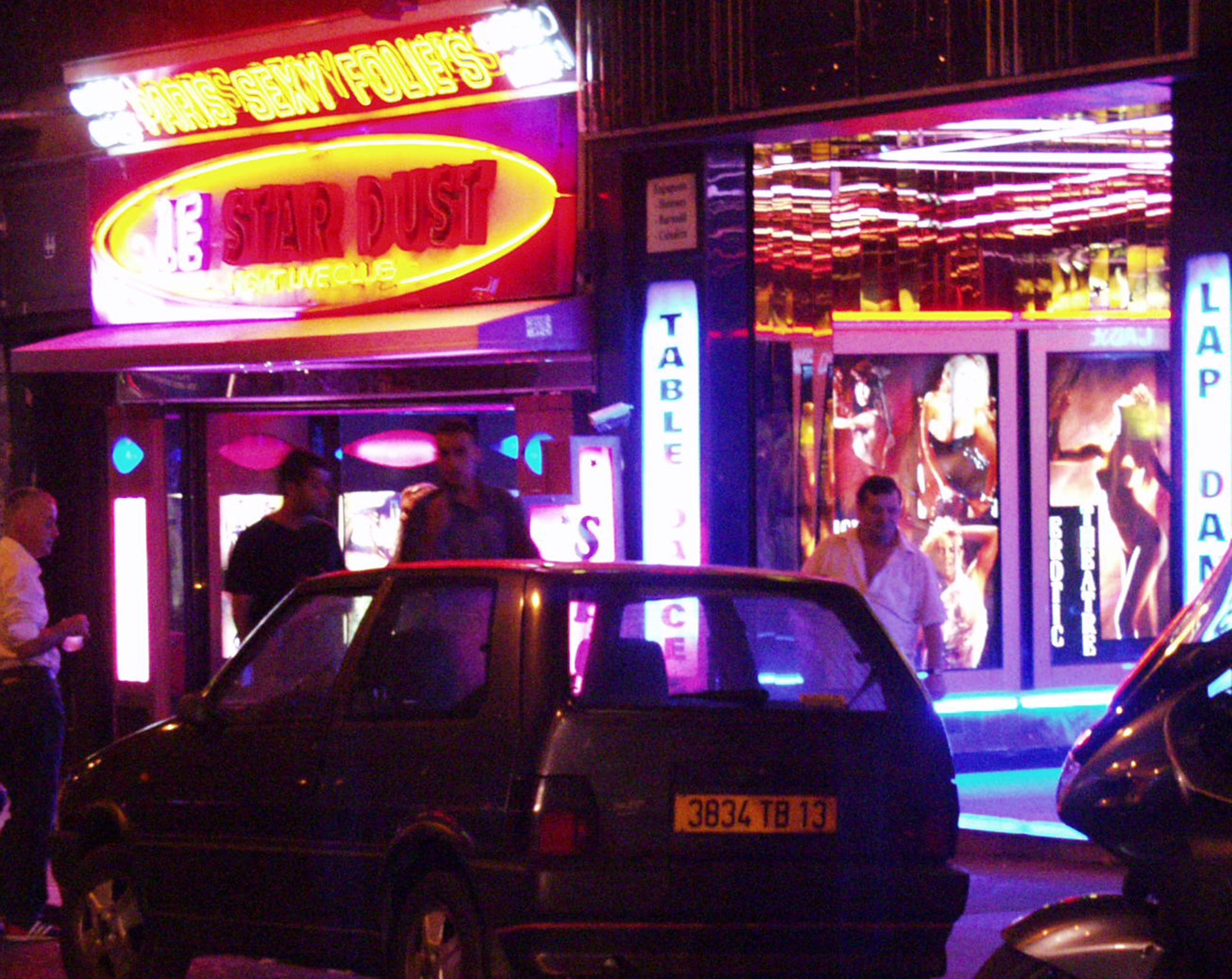Pigalle at night: neon of Paris Sexy Folie's and Le Star Dust over parked cars