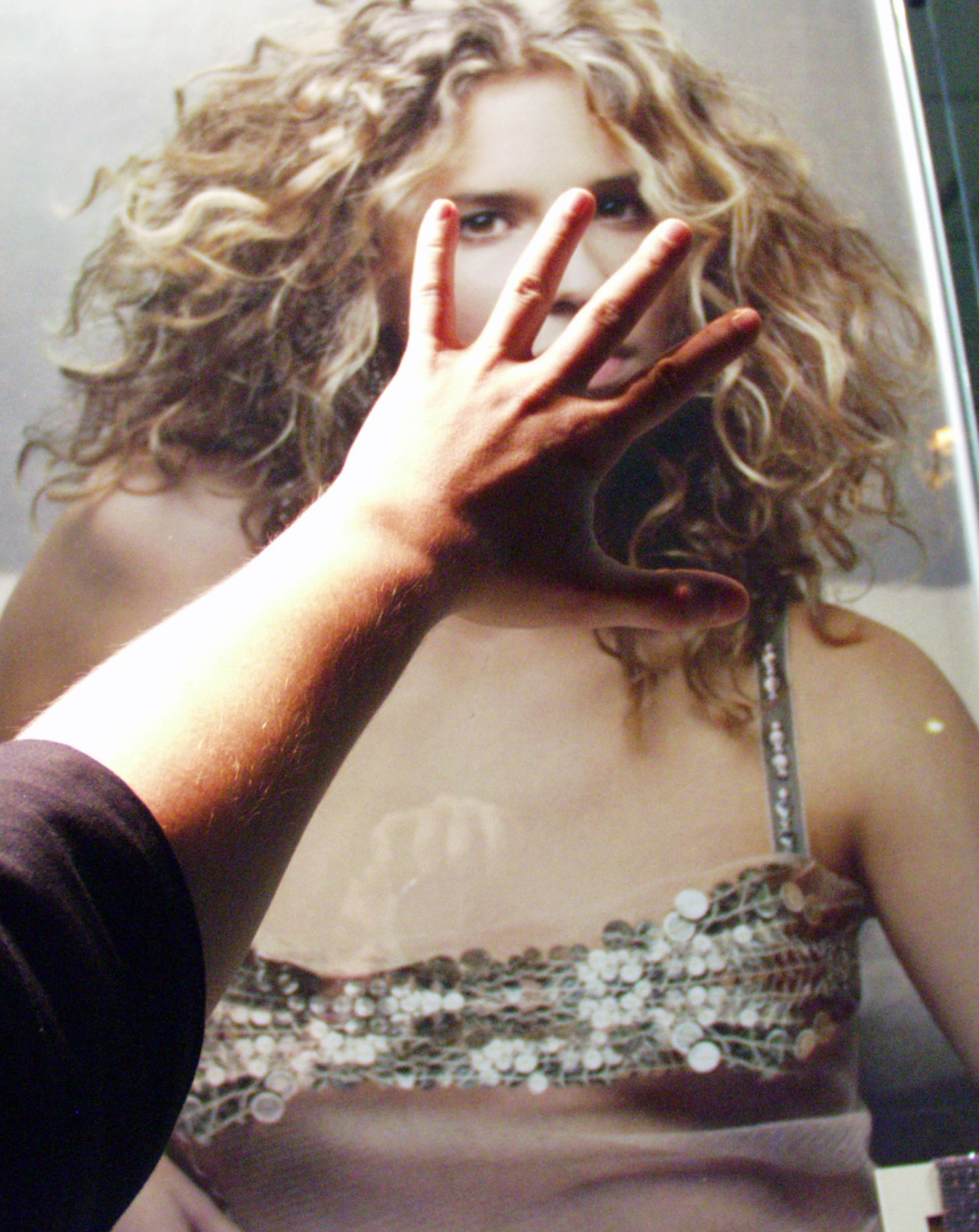 A hand pressed over the face of a woman on a poster