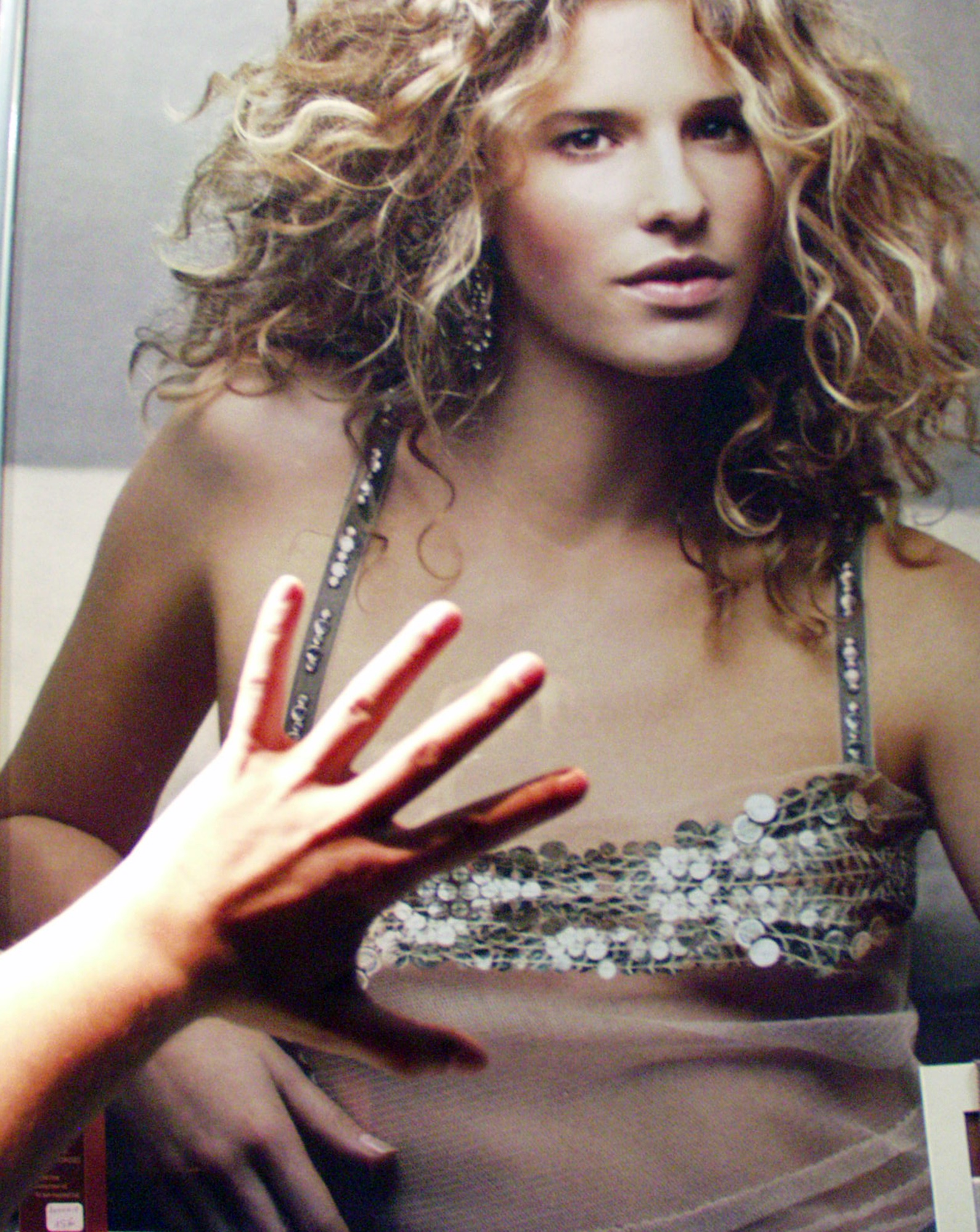Poster of a woman in a sequinned top, a hand spread across her