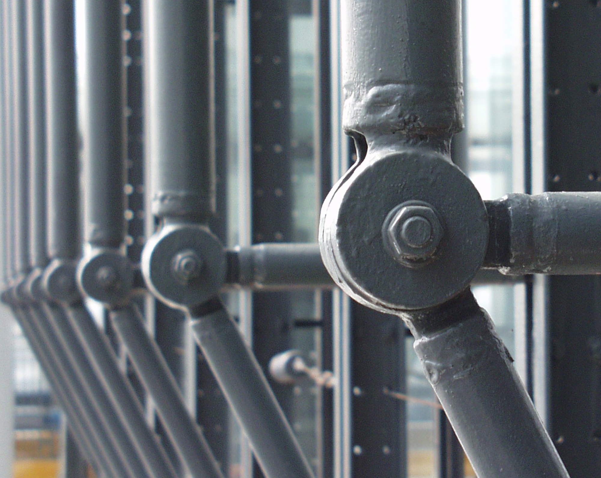 Grey steel bracing and round joints repeating along a glass façade