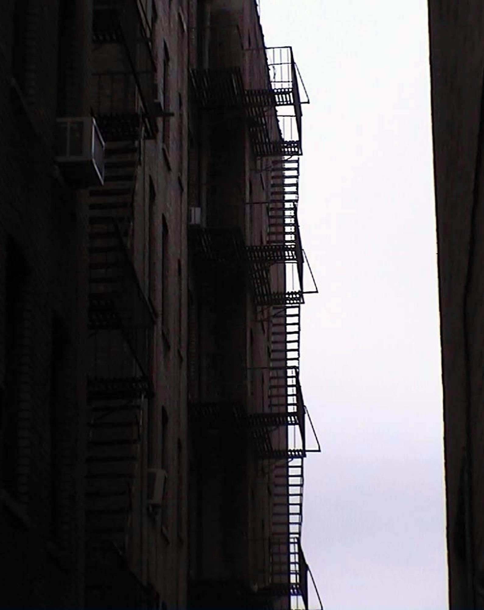 Fire escapes up a narrow gap between two buildings