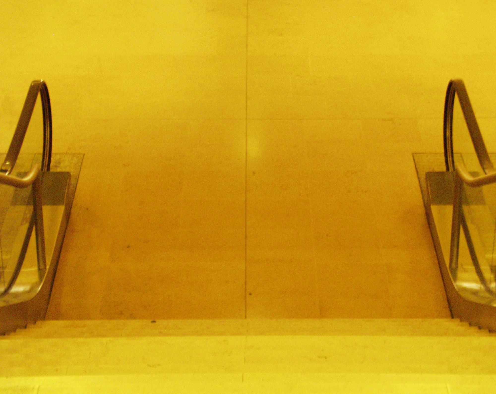 Escalators in a corridor washed in deep yellow light