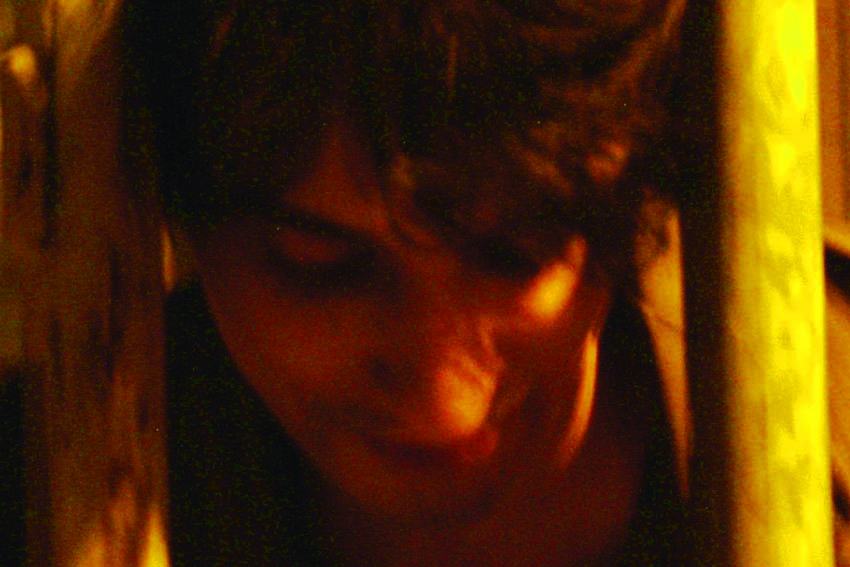 Face with eyes closed between two lit bars, amber light