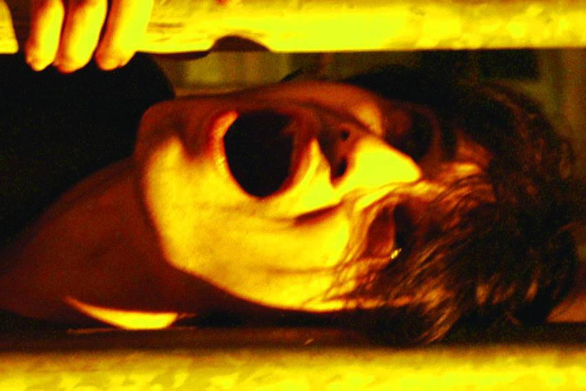 Face upside down between bars, mouth wide open, hand gripping above