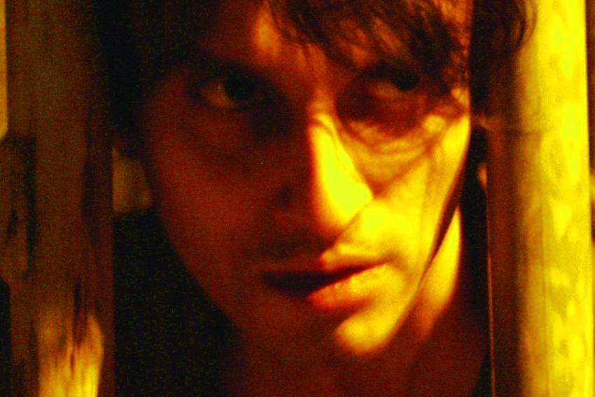 Face looking out between two bars in yellow light