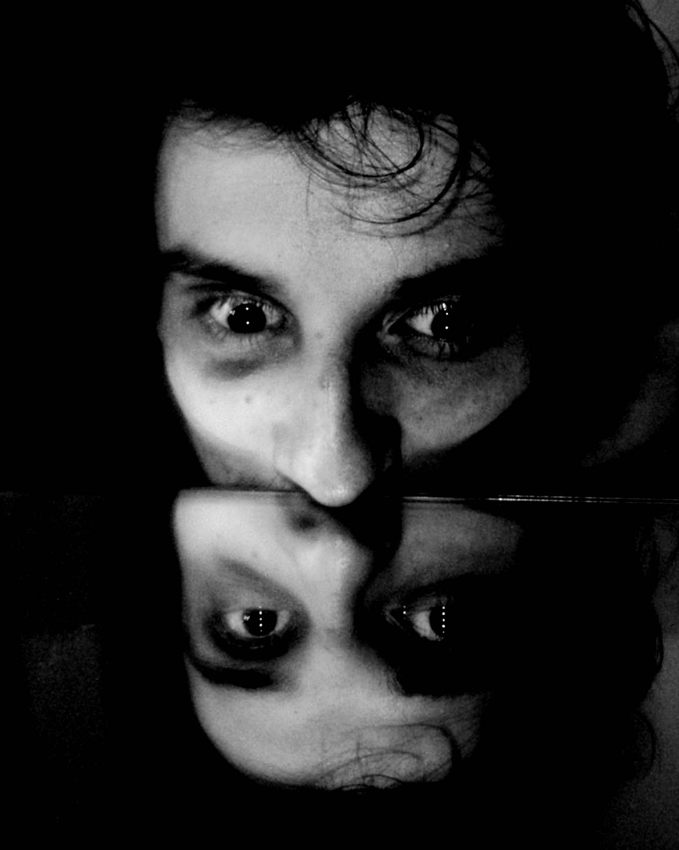Black and white face cut at the nose by a mirror, reflected upside down