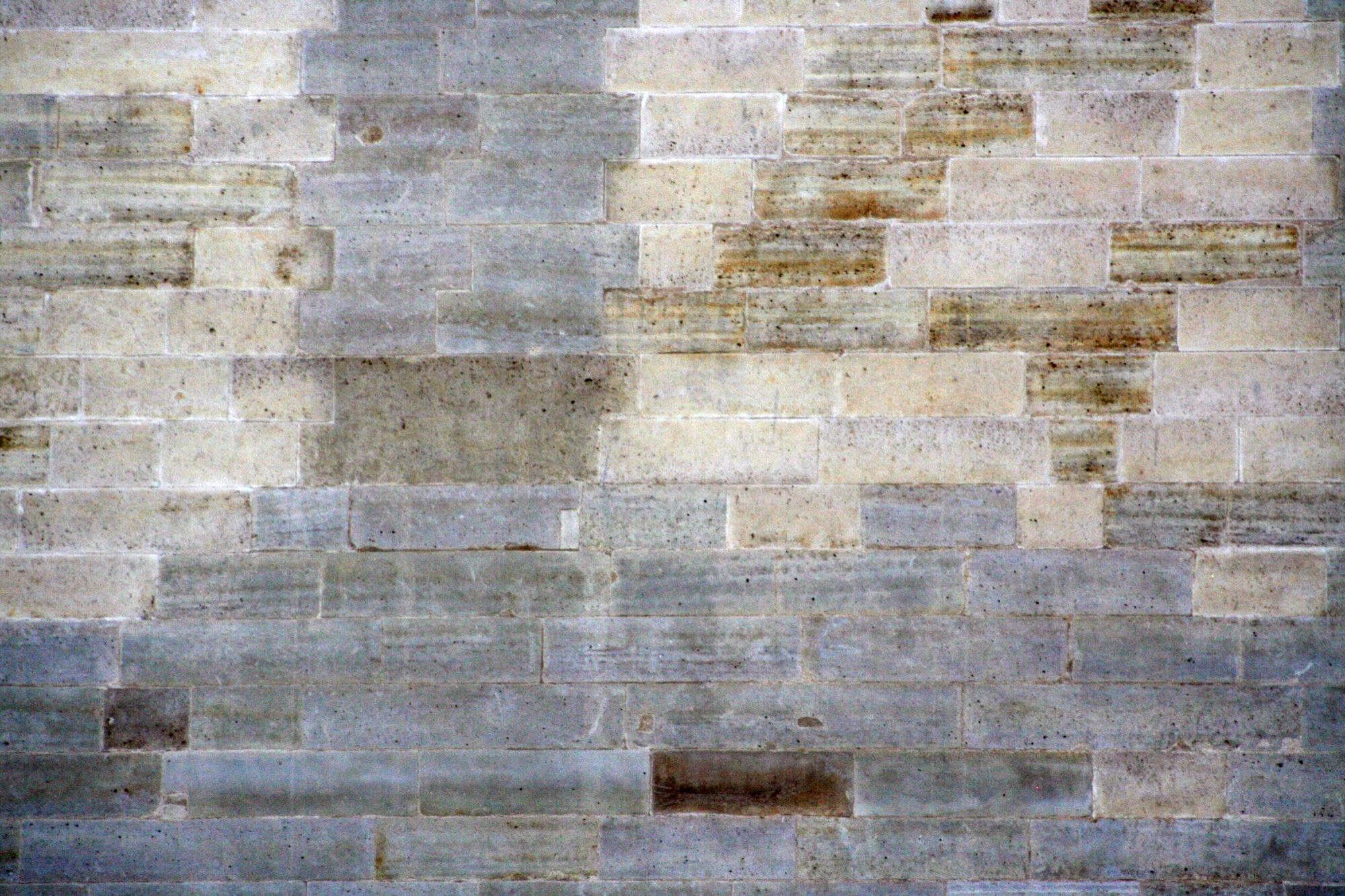 Old stone wall of pale blocks with rust stains