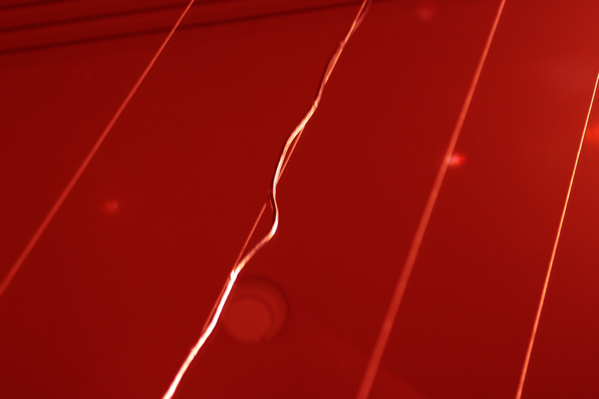 Red lacquered surface crossed by thin lines of light