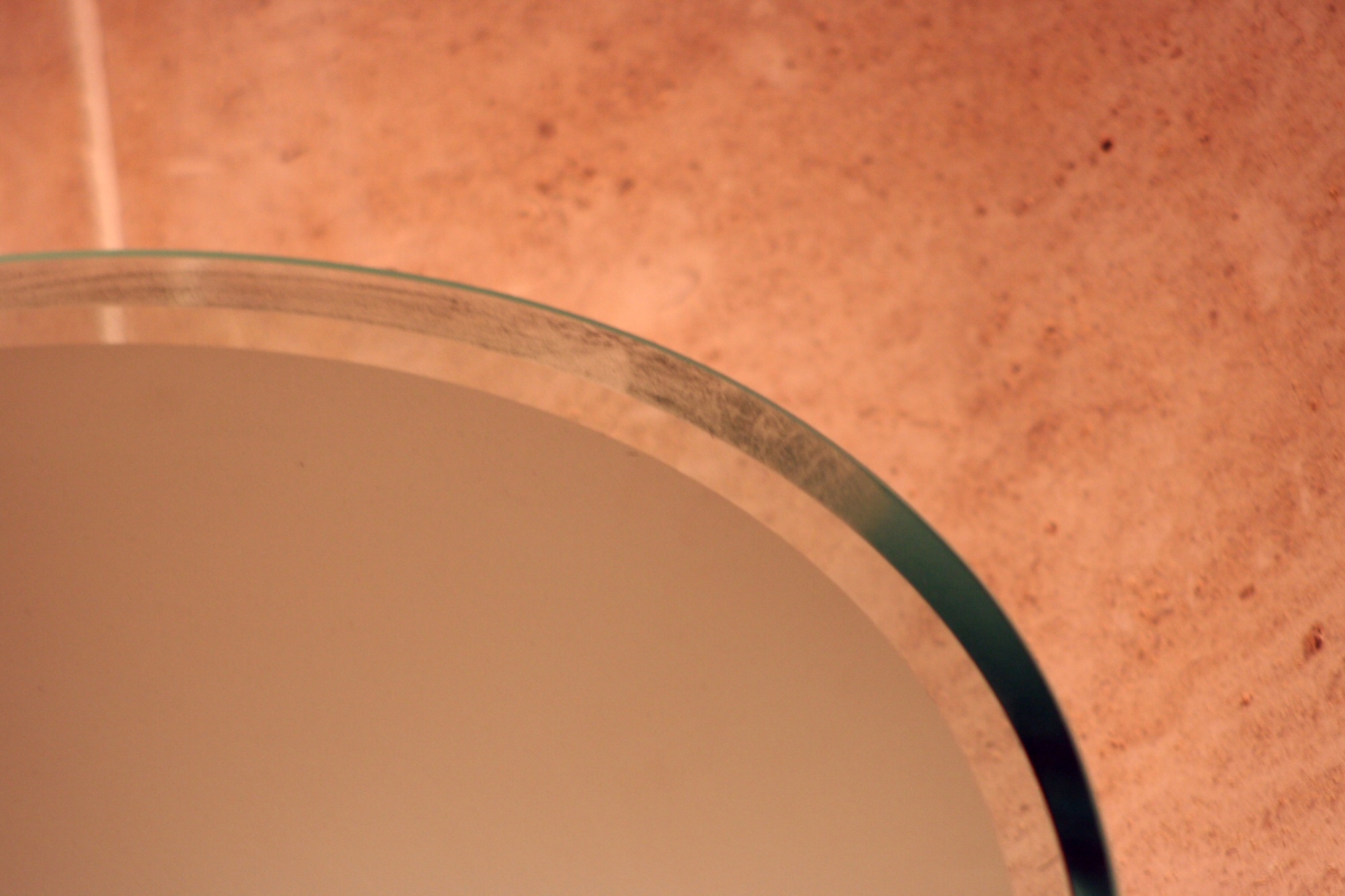 The curved edge of glass over a pink surface